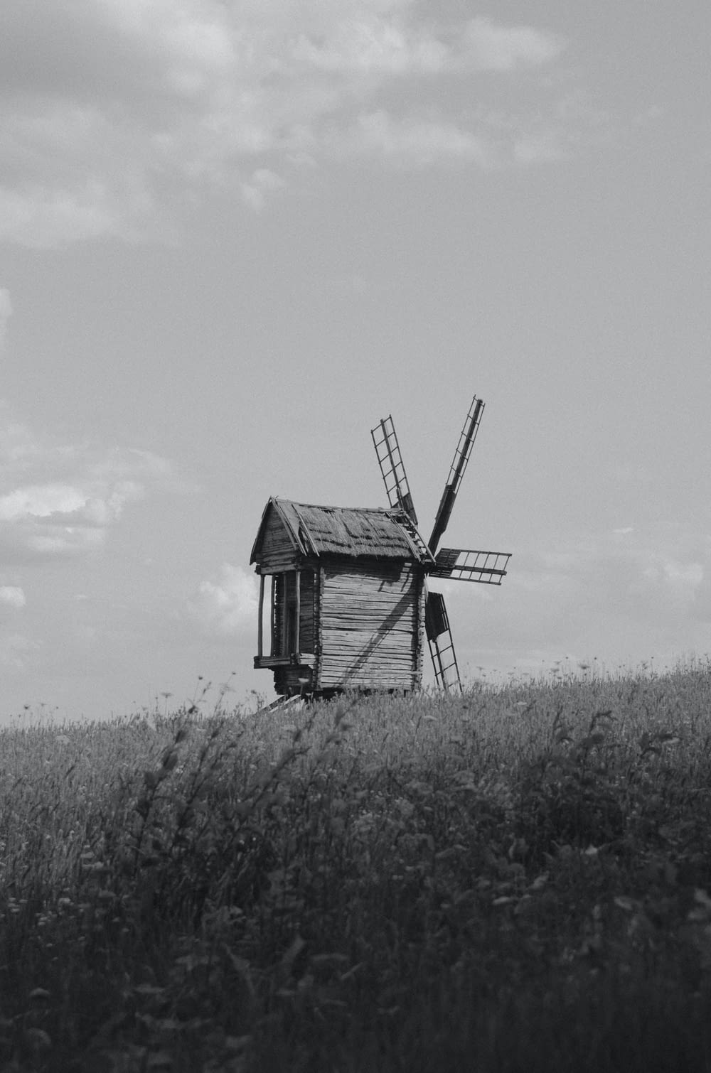 a black and white photo of a windmill in a field