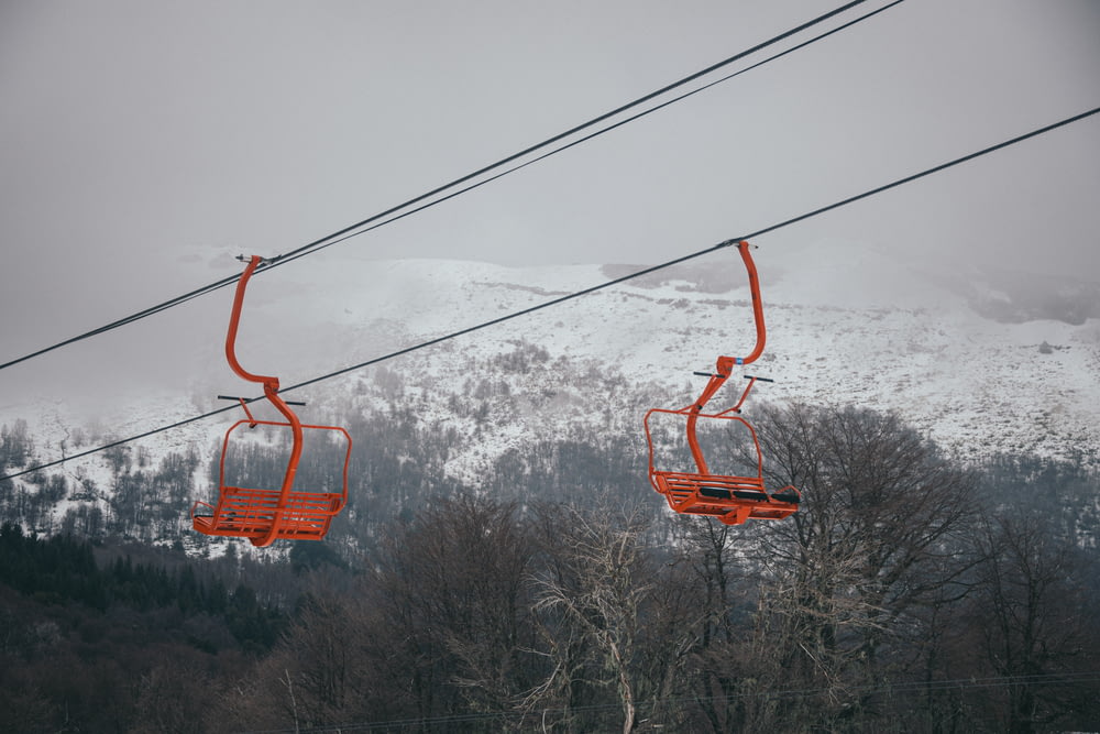 a couple of orange chairs sitting on top of a ski slope