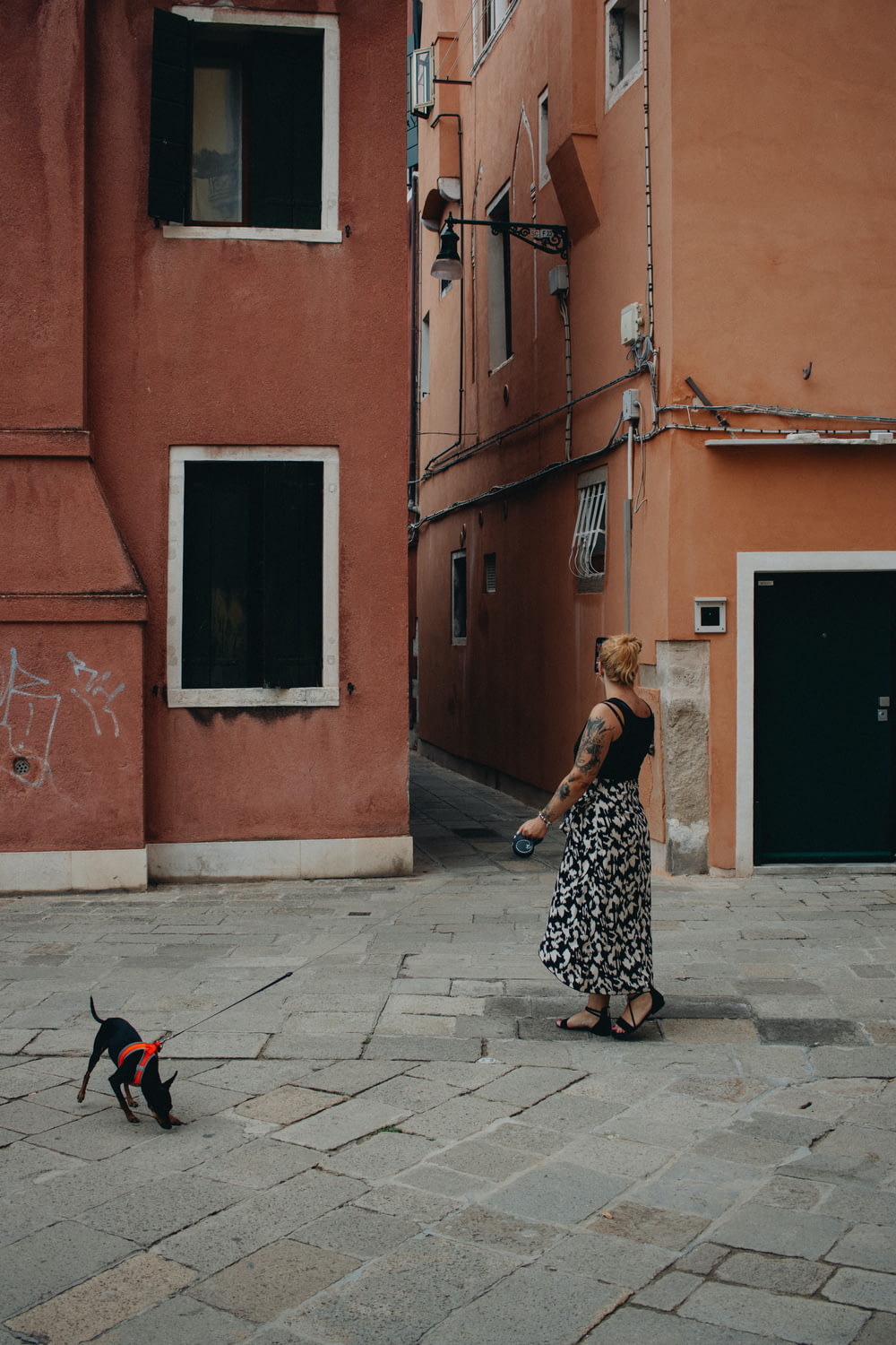 a woman walking a dog on a city street