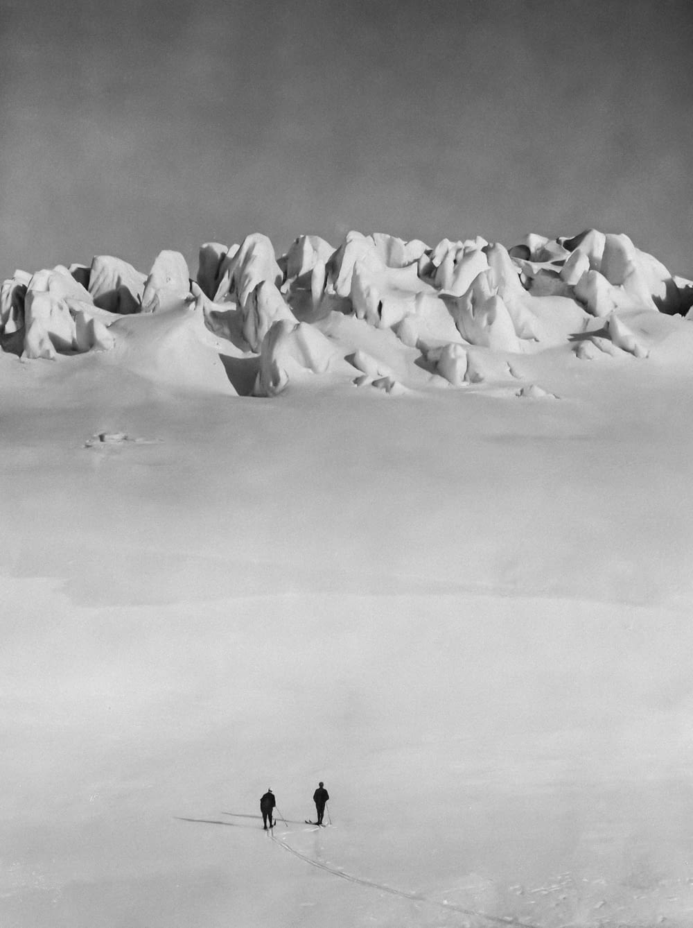 a couple of people walking across a snow covered field