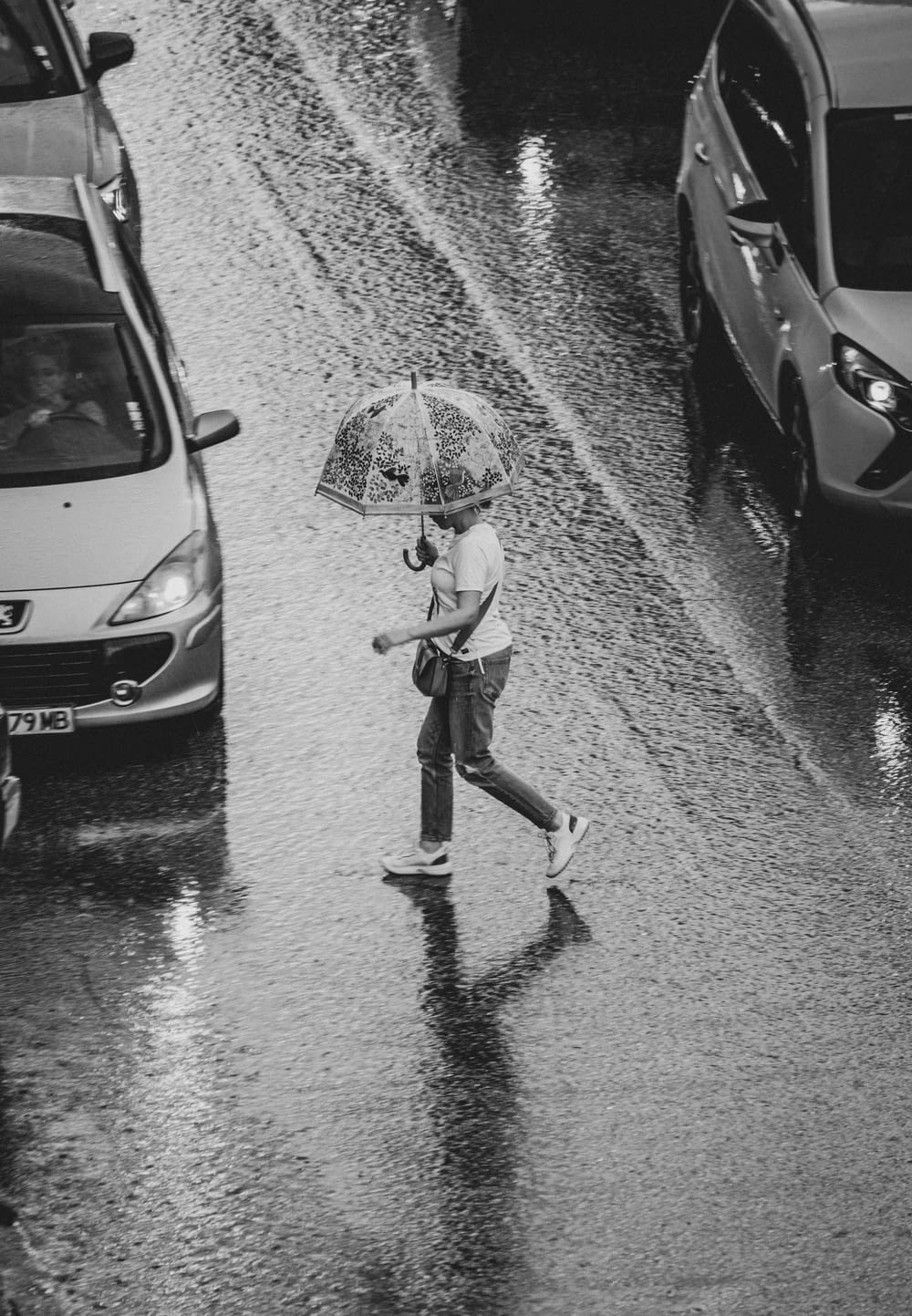 a black and white photo of a person walking in the rain with an umbrella