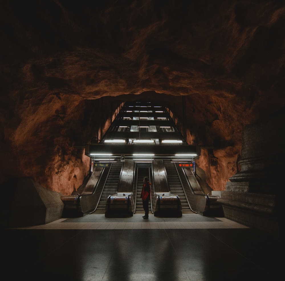 a person standing in front of an escalator in a cave