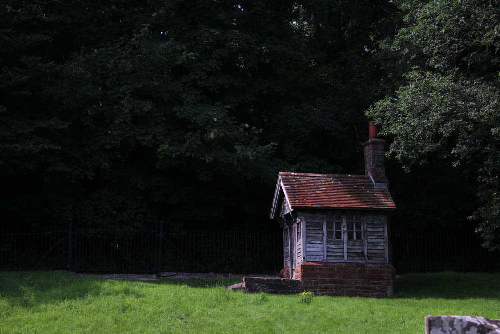 a small building sitting in the middle of a lush green field