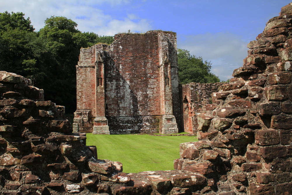 the ruins of a castle with a green lawn in the foreground