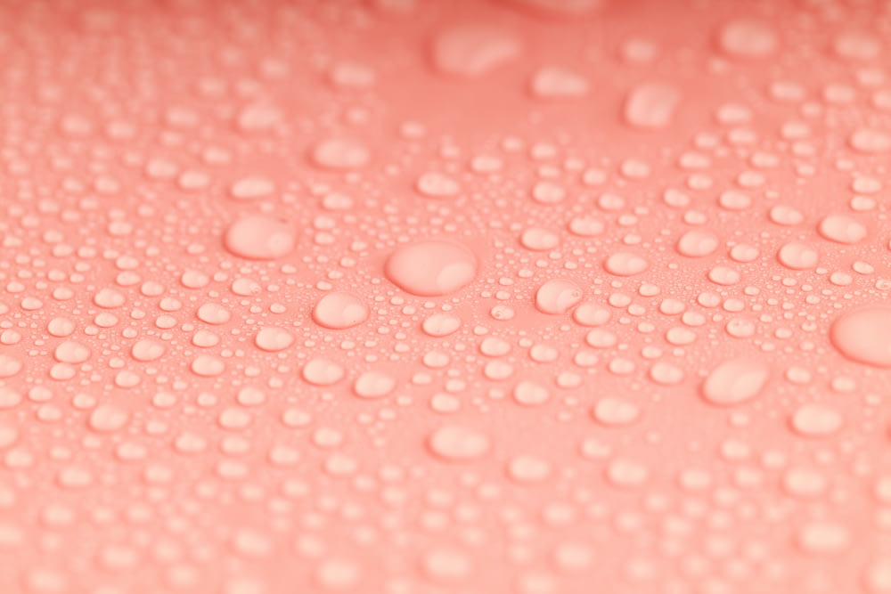 a close up of water droplets on a pink surface