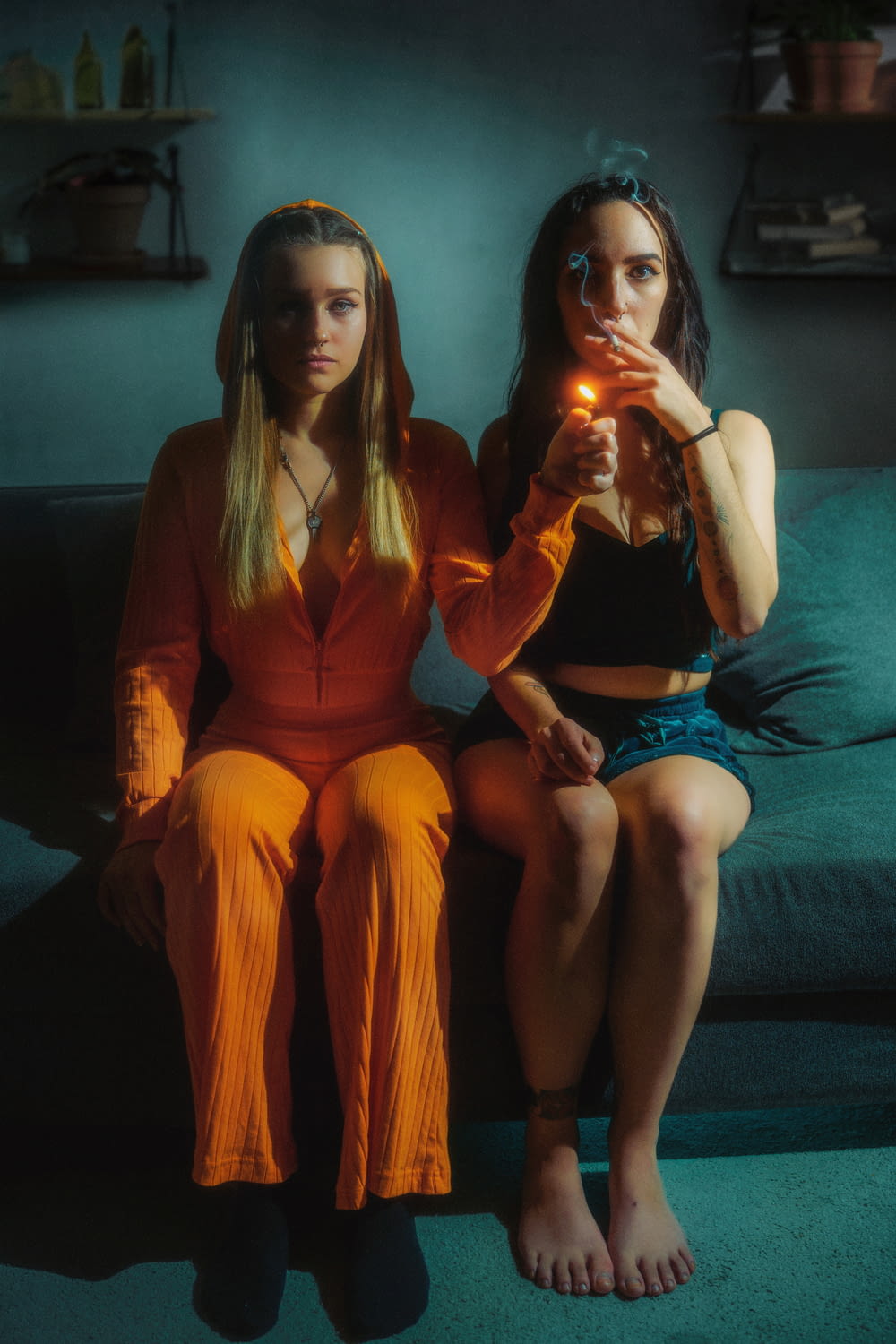 two women sitting on a couch holding a lit candle