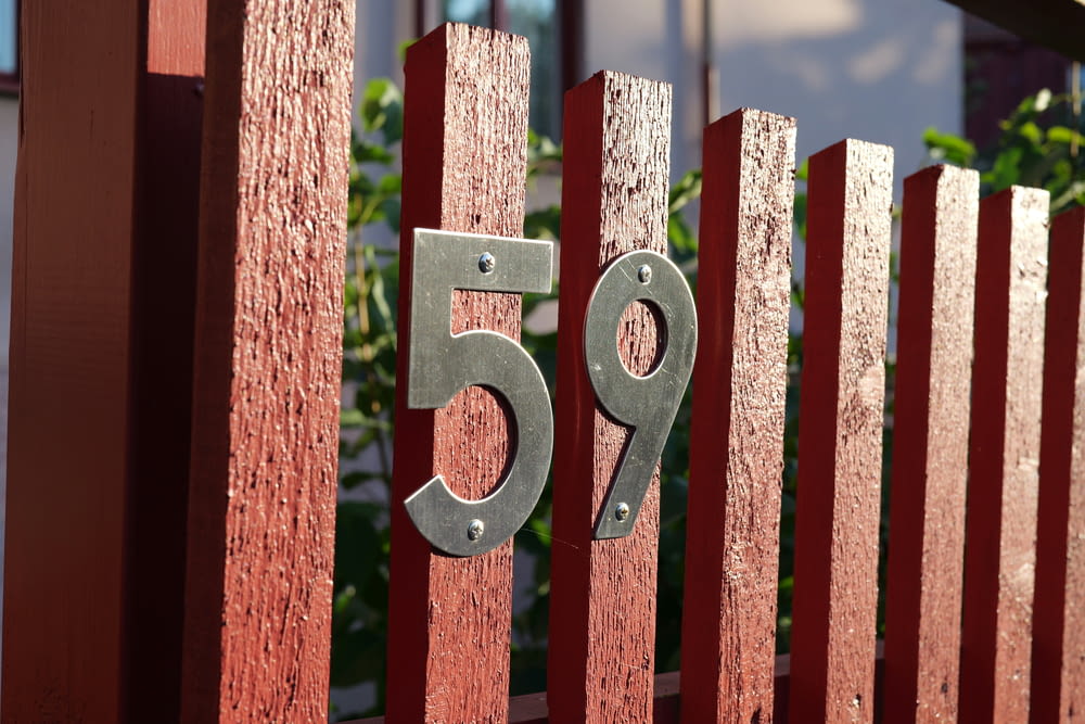 a red fence with a metal number on it