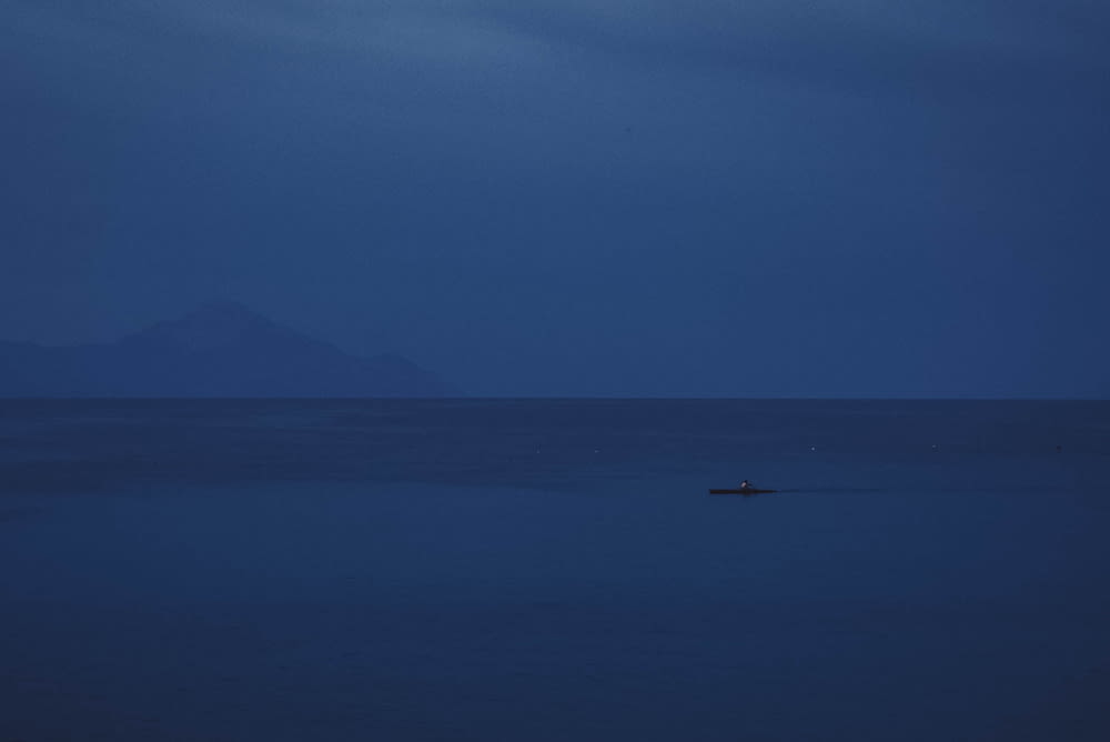 a lone boat in the middle of the ocean at night