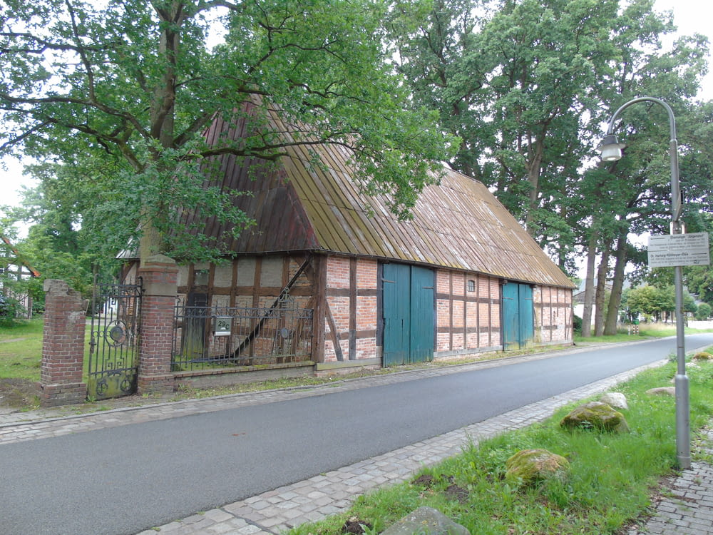 an old brick building with a thatched roof next to a road