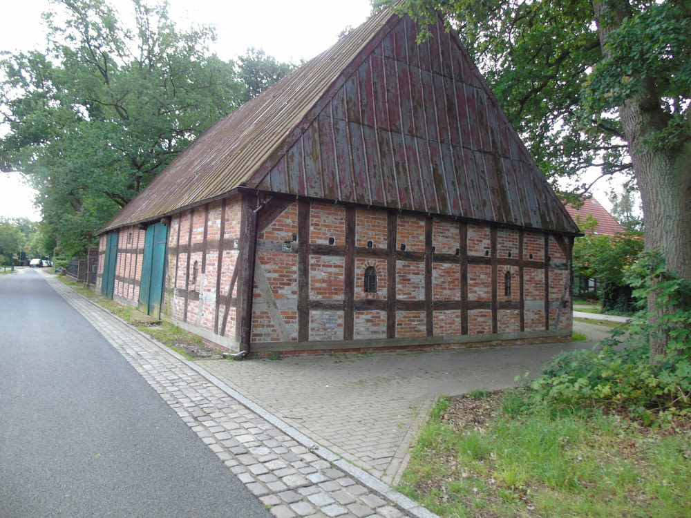 a brick building with a thatched roof next to a tree