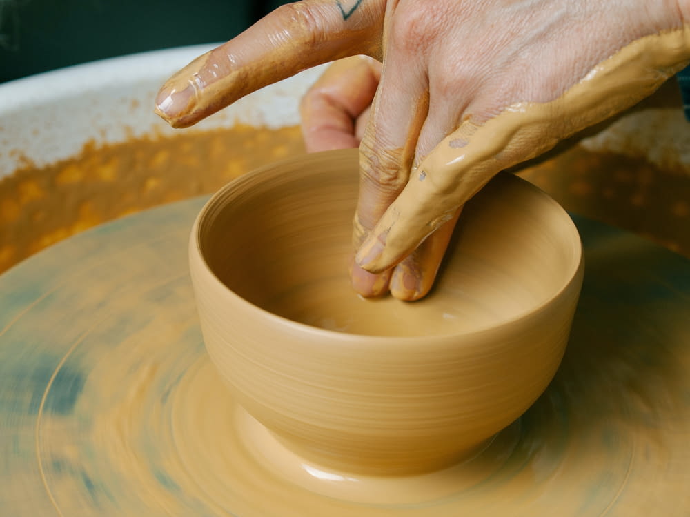 a person making a bowl on a pottery wheel