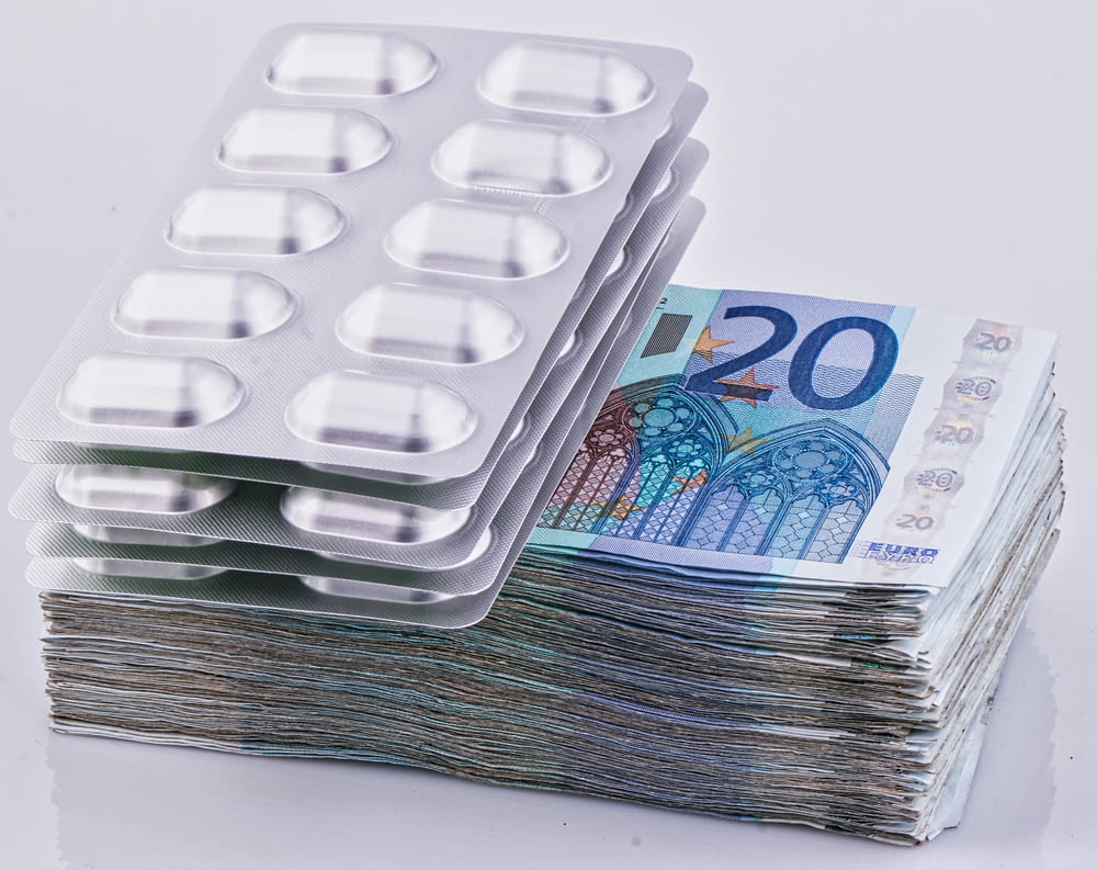 ein Stapel 20-Euro-Scheine neben einer Packung mit 20 Pillen