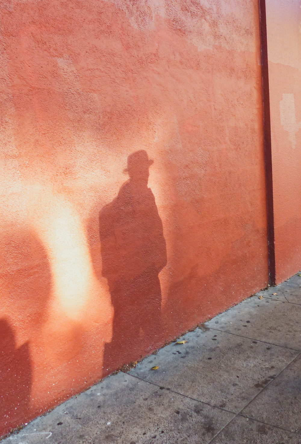 a shadow of a man standing next to a red wall
