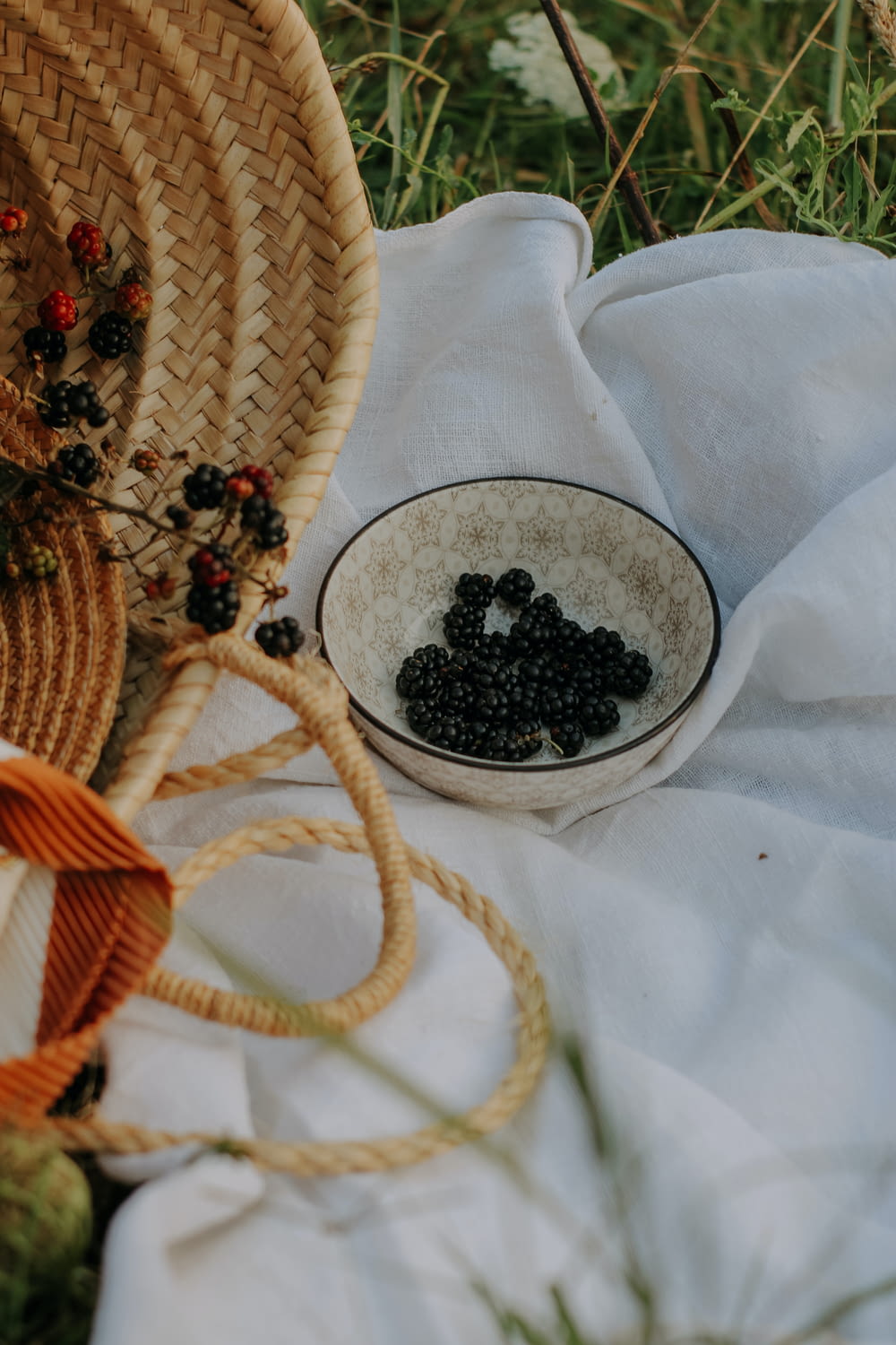 a bowl of blackberries on a white cloth