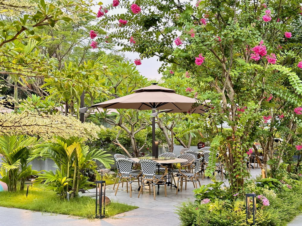 a patio with tables, chairs and umbrellas surrounded by trees