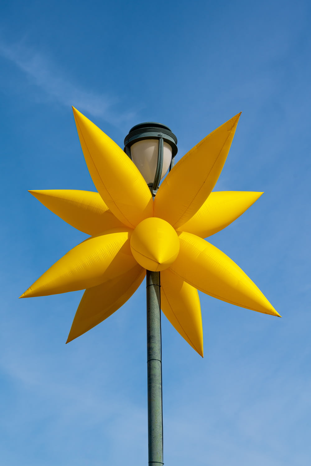 a street light with a large yellow flower on it