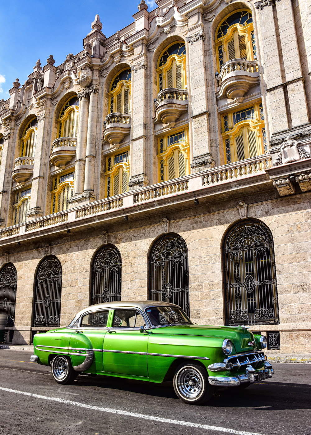 a green classic car parked in front of a building
