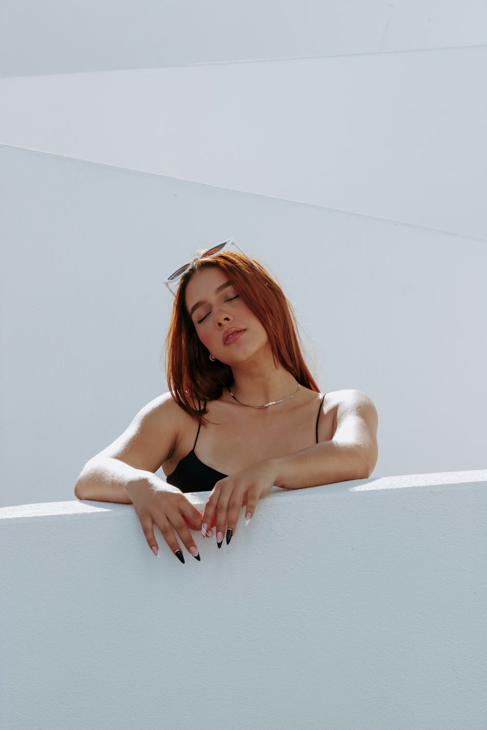 a woman with red hair leaning on a wall