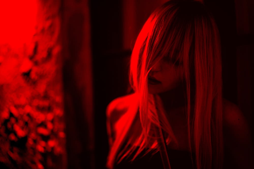 a woman standing in a dark room with a red light