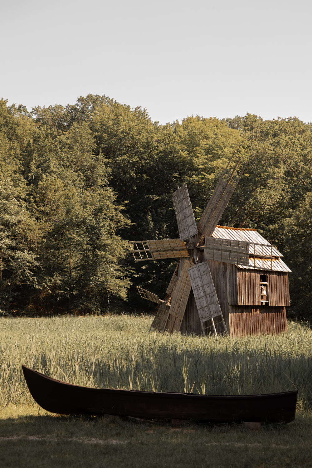 a boat sitting in a field next to a windmill