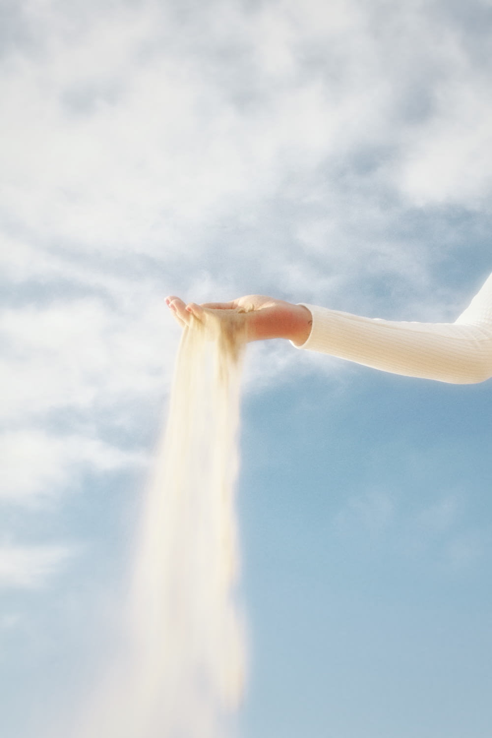 a woman is holding out her arm with a spray of sand