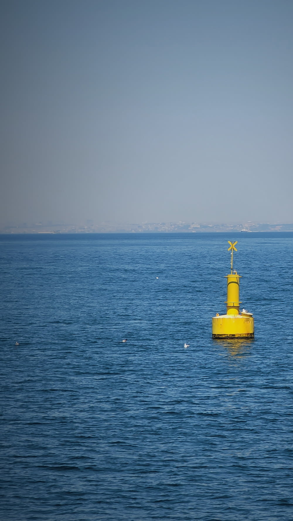 a yellow buoy floating in the middle of the ocean