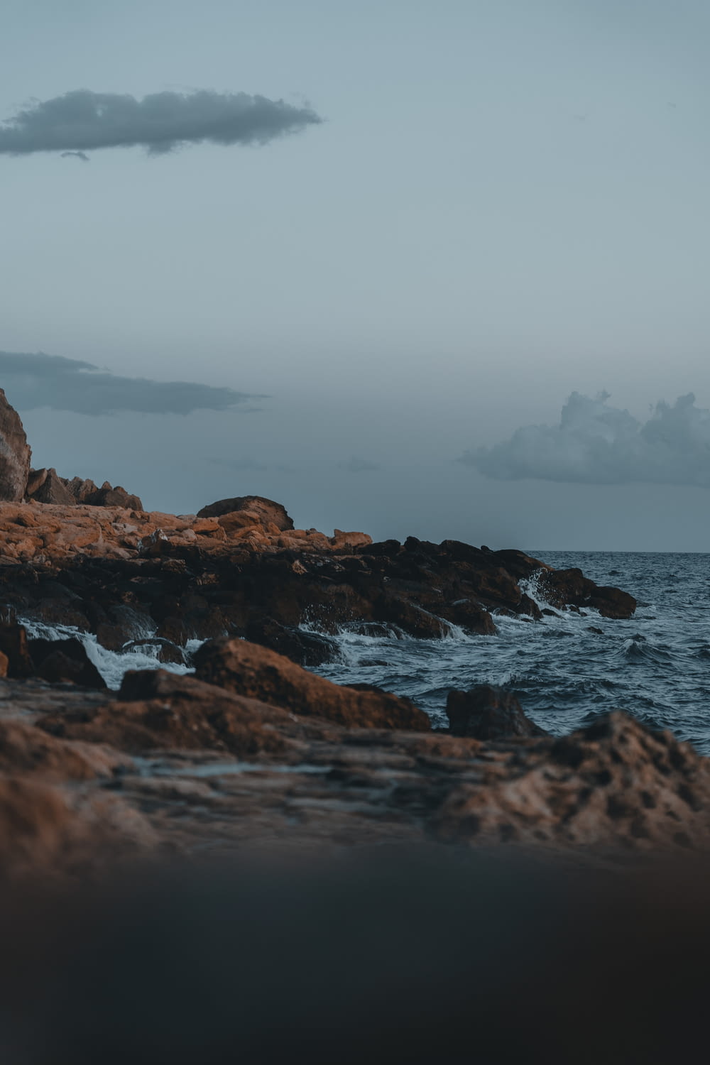a person standing on a rocky shore next to the ocean