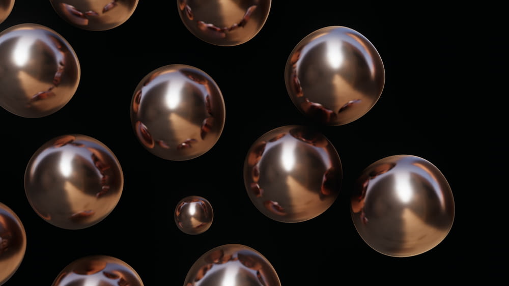 a bunch of shiny metallic balls on a black background