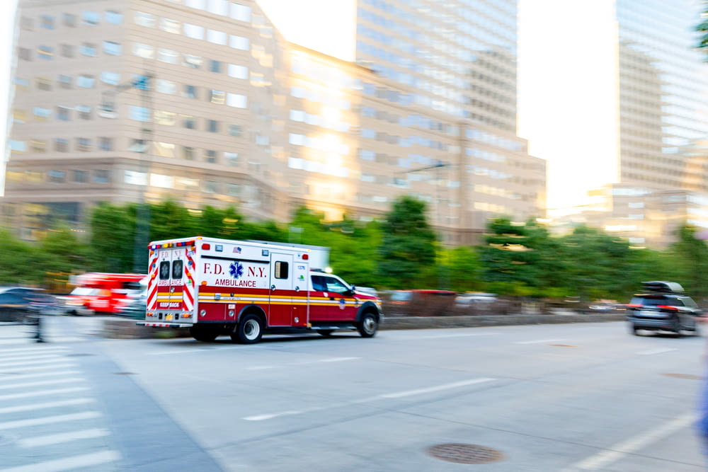 an ambulance driving down a city street next to tall buildings