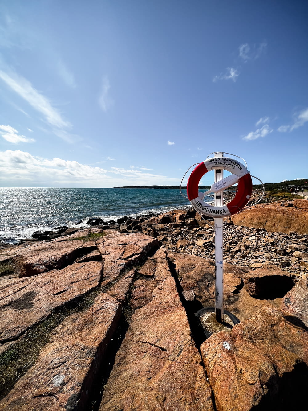 a red and white sign sitting on top of a rocky beach
