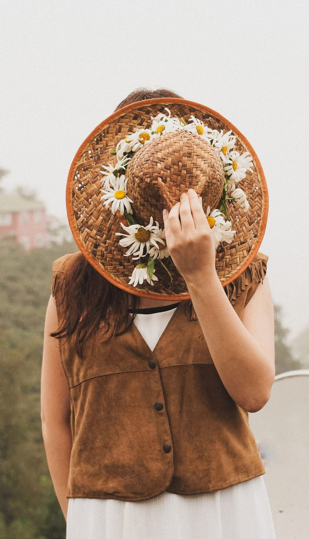 a woman wearing a straw hat with daisies on it