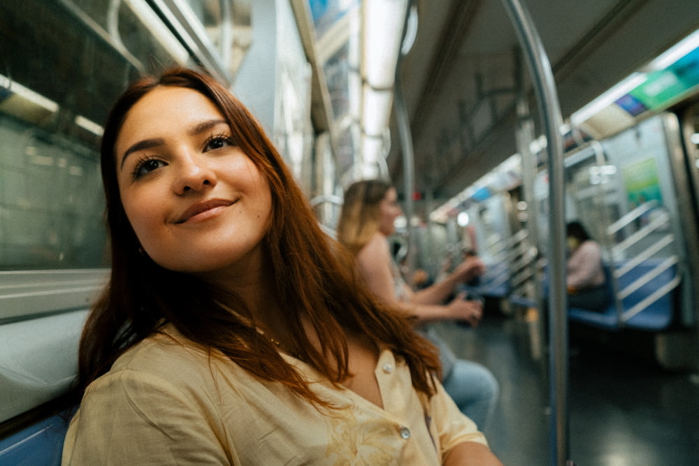 a woman is sitting on a subway train