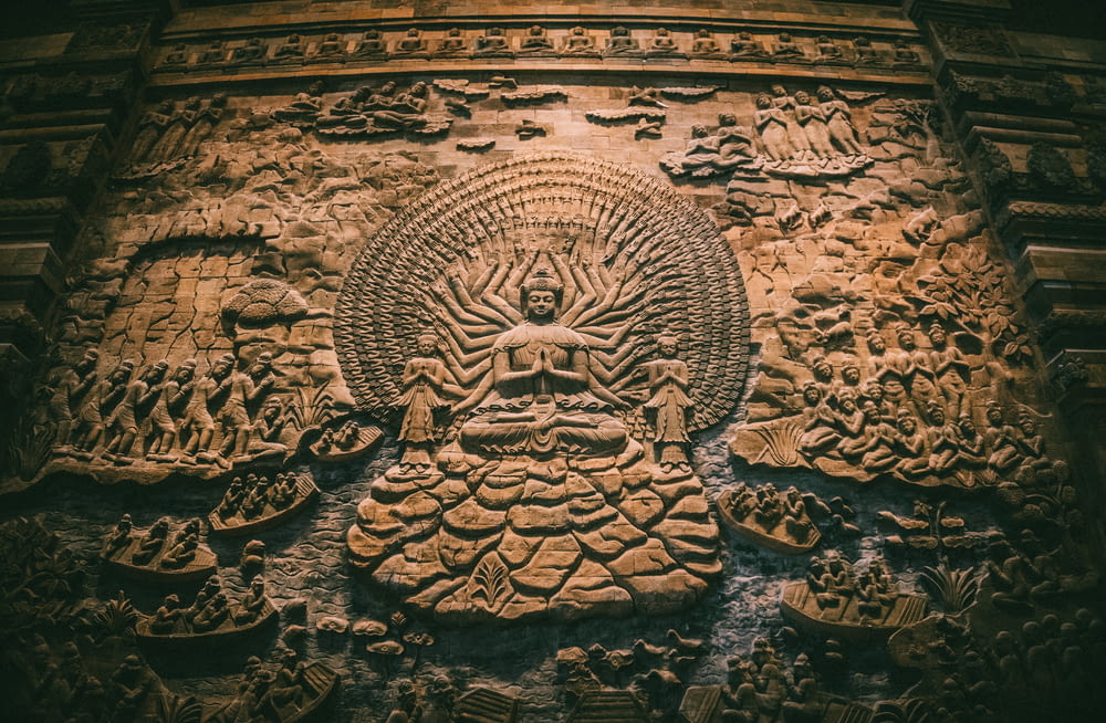a stone carving of a buddha surrounded by other carvings