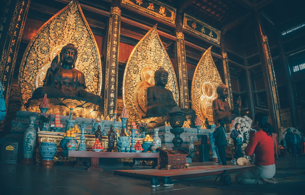 a group of people sitting in front of buddha statues