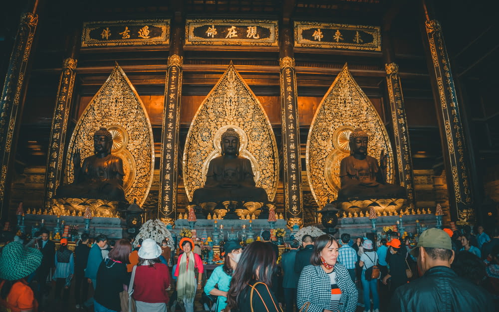 a group of people standing in front of a golden buddha statue
