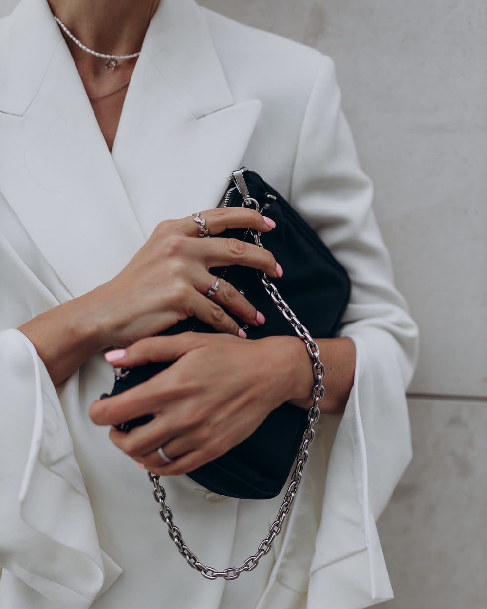 a woman in a white suit holding a black purse