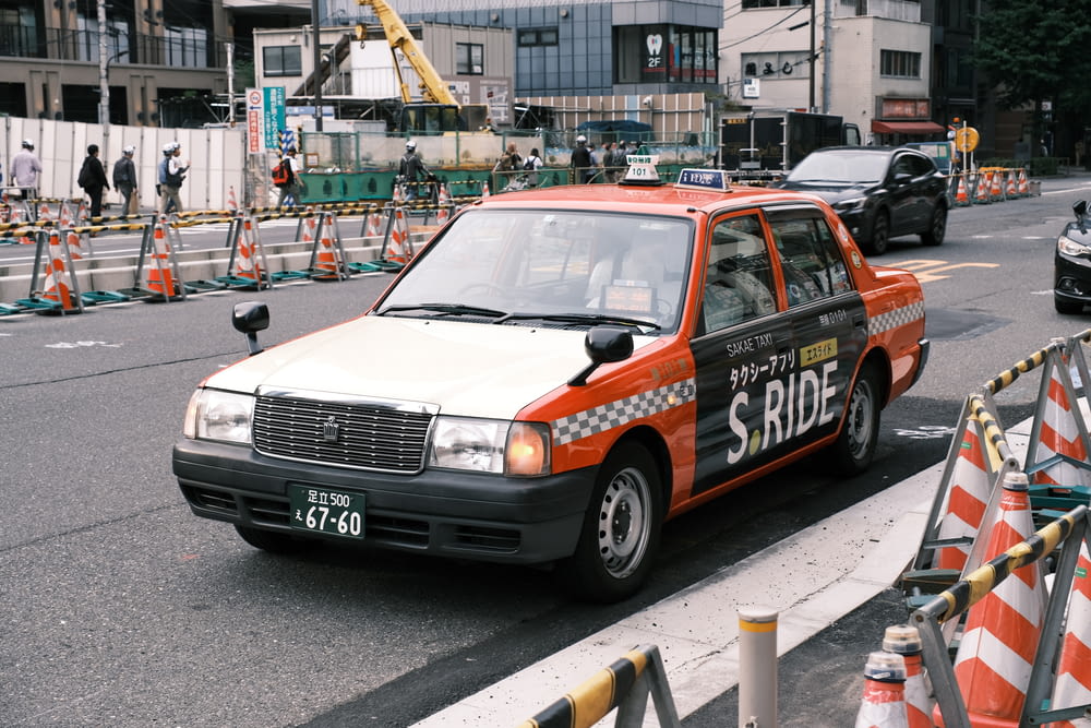 an orange and white police car driving down a street