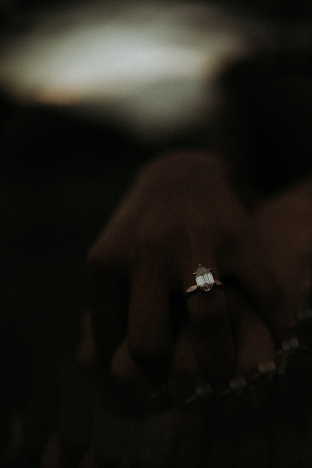 a close up of a person's hand holding a diamond ring