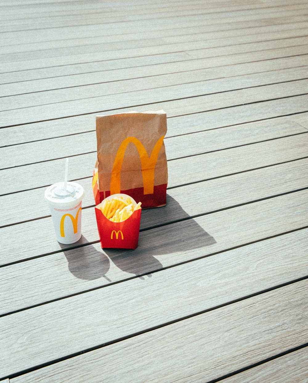 a mcdonald's bag sitting on a wooden deck next to a cup of coffee