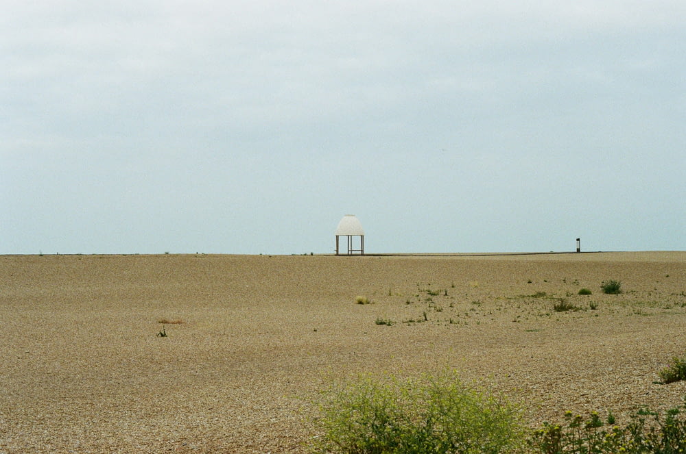 a small white structure in the middle of a desert
