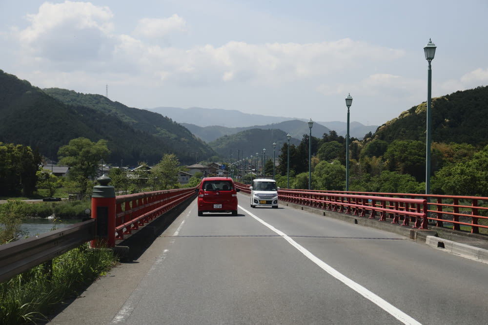 a red bus driving across a bridge over a river
