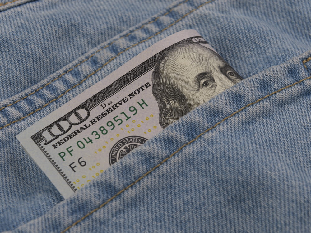 a hundred dollar bill sticking out of the back pocket of a pair of jeans