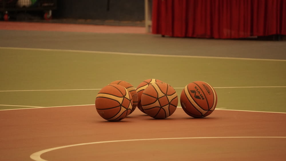赤いカーテンを背景にバスケットボールコートに座っている3つのバスケットボール
