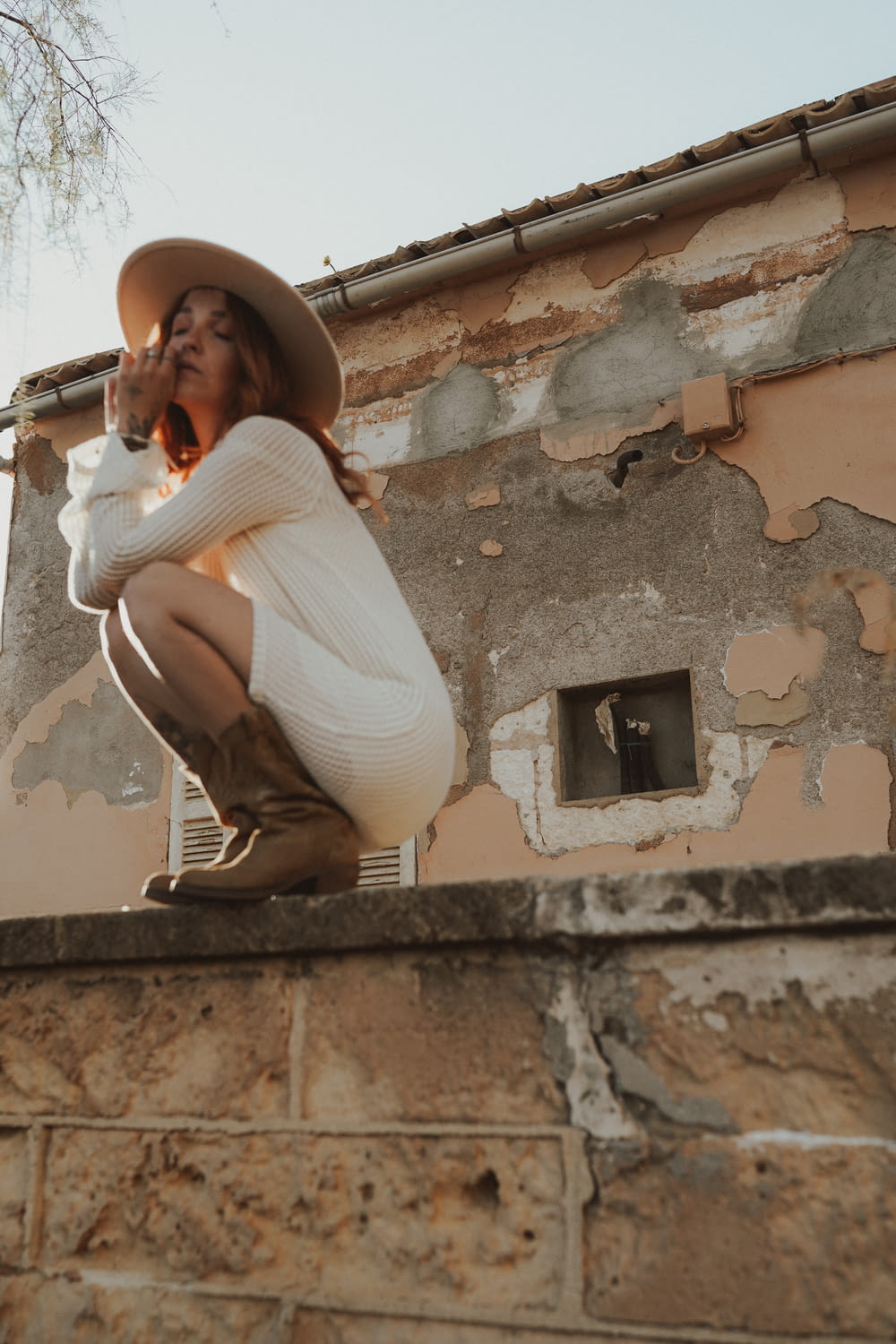 a woman sitting on a wall with a hat on