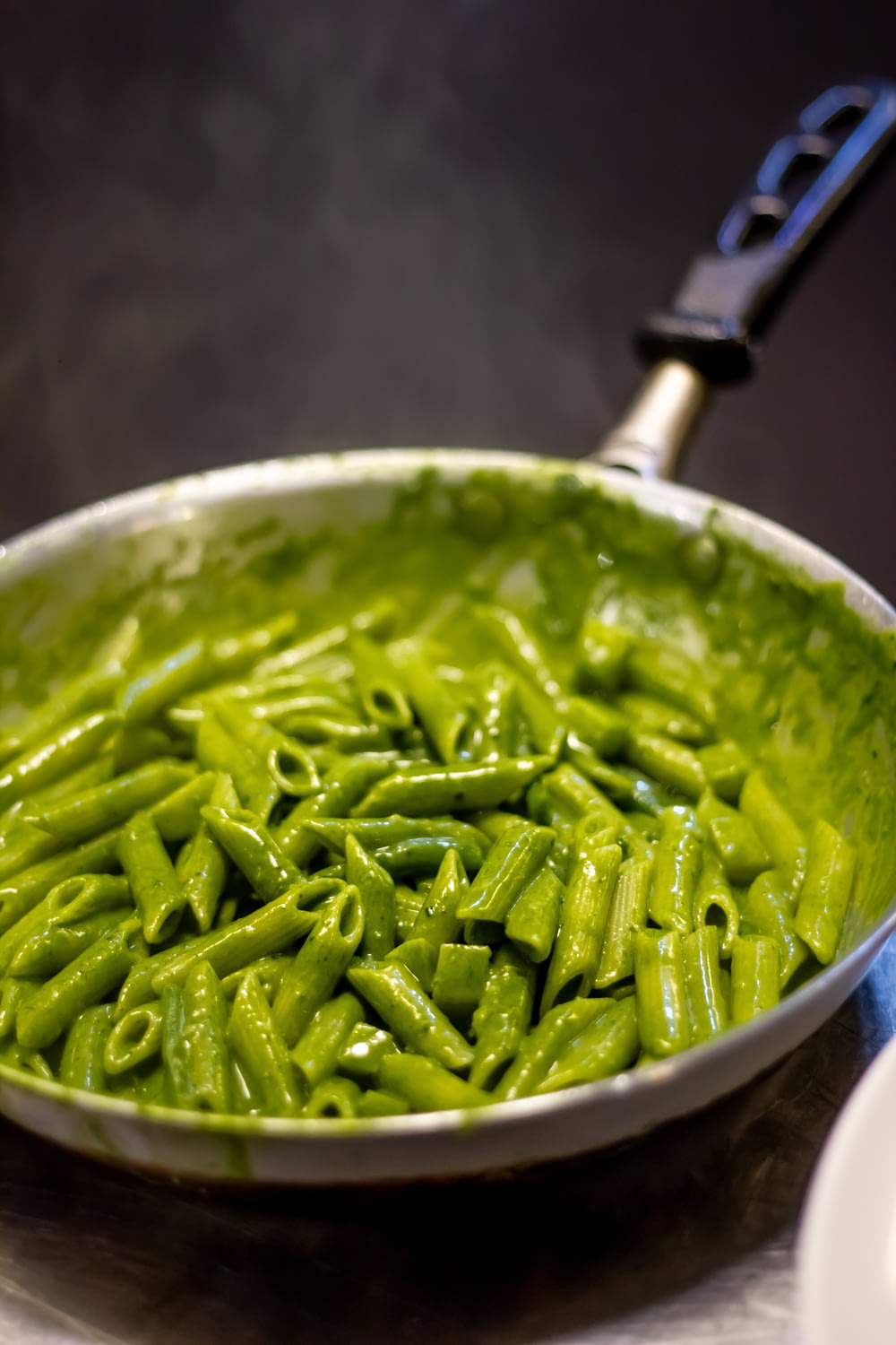 a pan filled with green pasta on top of a stove