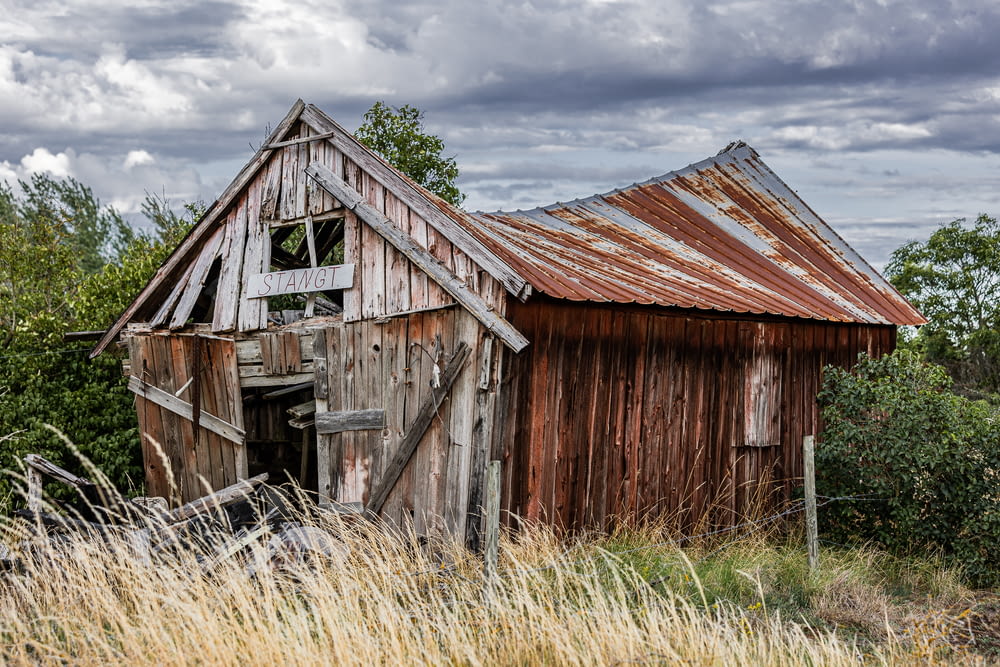 an old wooden barn with a rusty roof