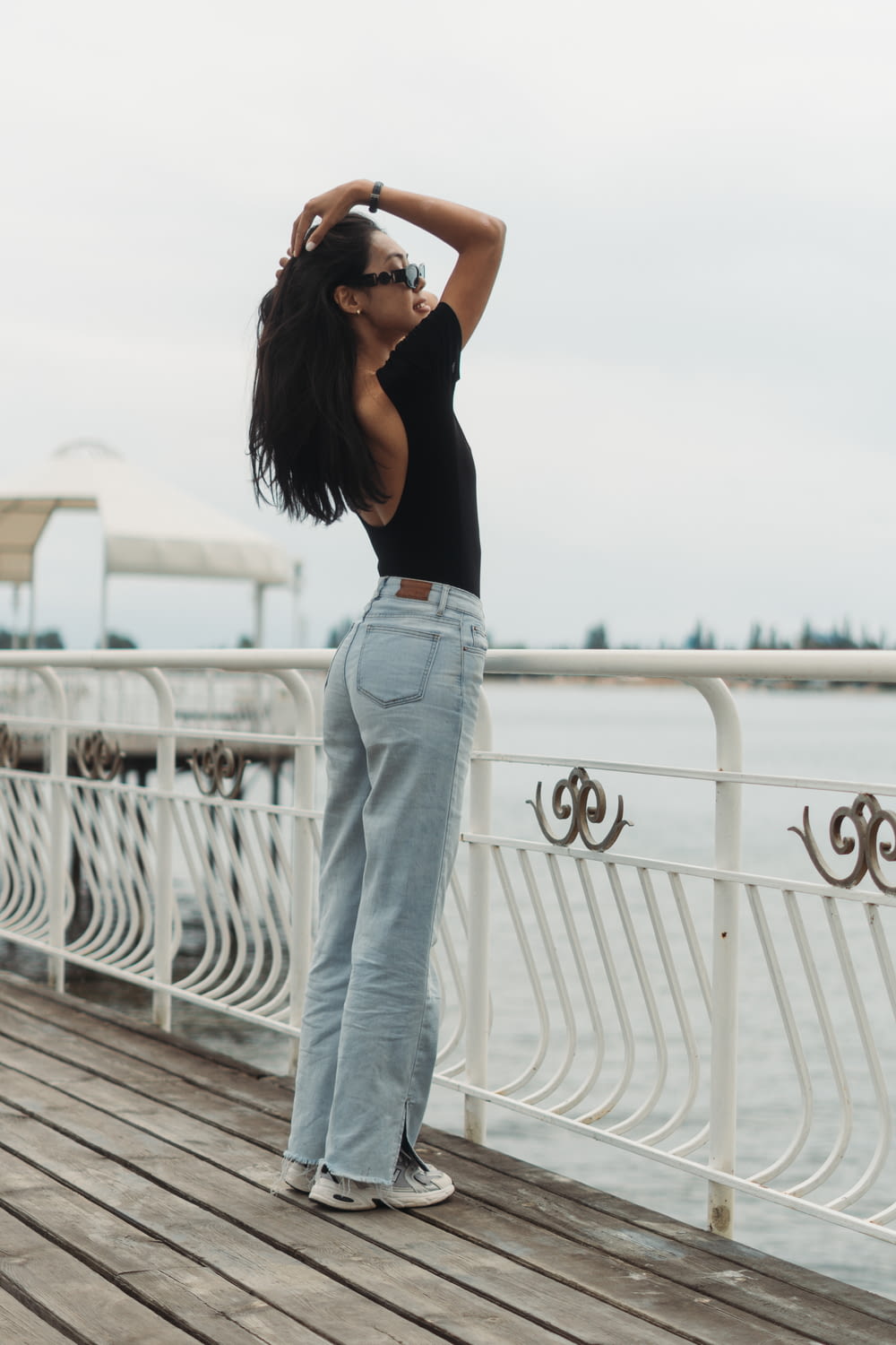 a woman standing on a pier with her hands behind her head