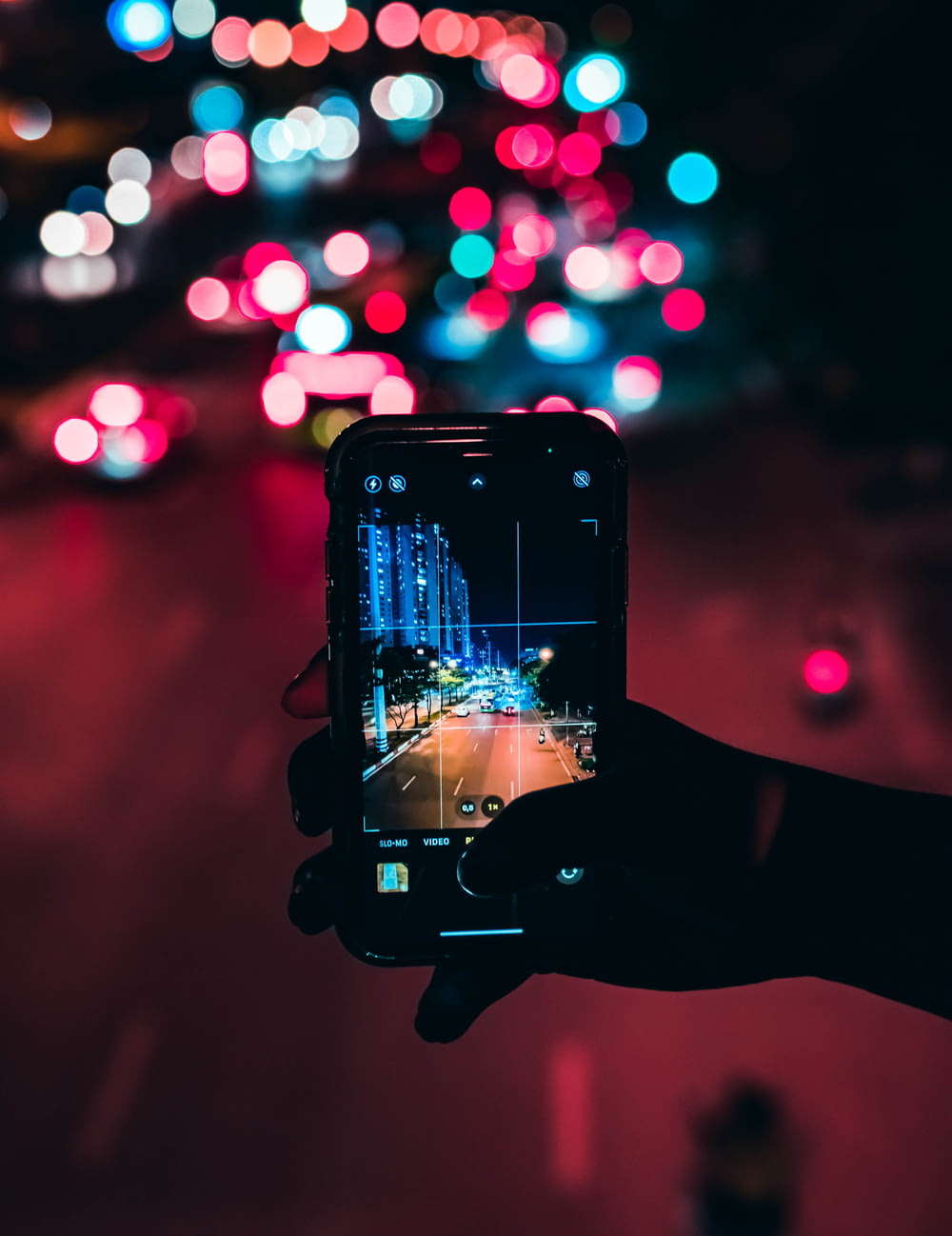 a person taking a picture of a city street at night