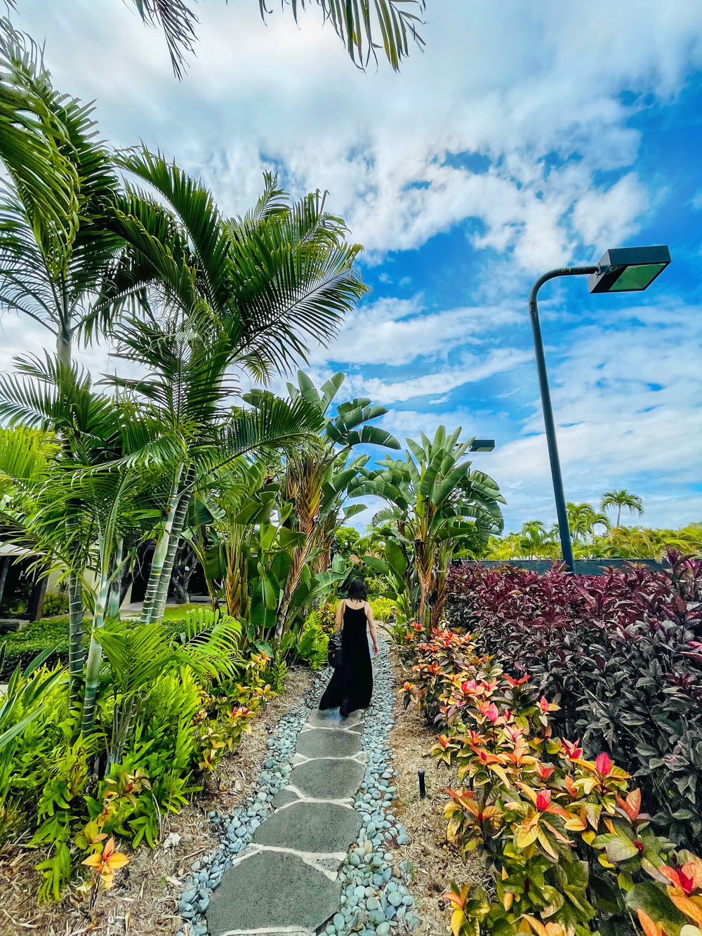 a woman walking down a pathway in a garden