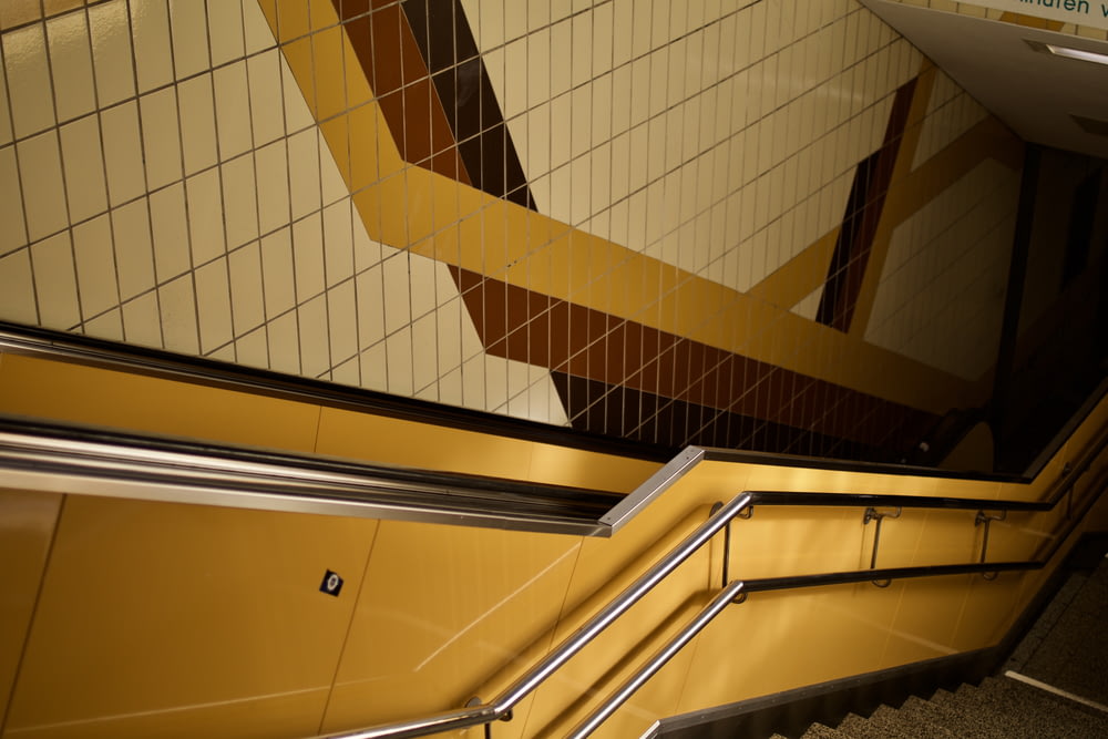 uma escada rolante em uma estação de metrô com paredes de azulejos